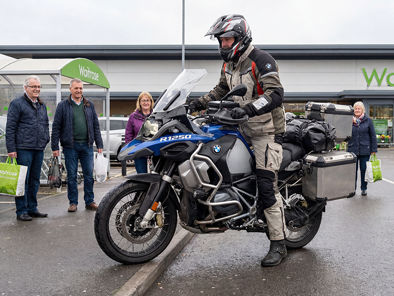 Man mounting a kerb on an adventure motorcycle in a Waitrose carpark